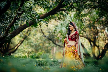 Offbeat bride in yellow and maroon lehenga outdoors