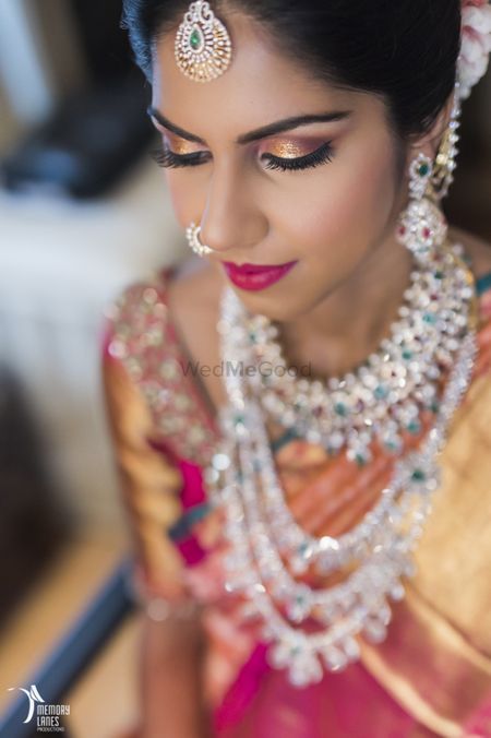 Photo of South Indian bride with gold eyes and emerald and diamond jewellery
