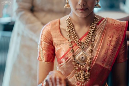Photo of A South Indian bride wearing a layered temple jewellery necklace.
