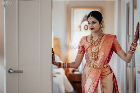 Photo of South Indian bride wearing a dual toned silk saree with temple jewellery.