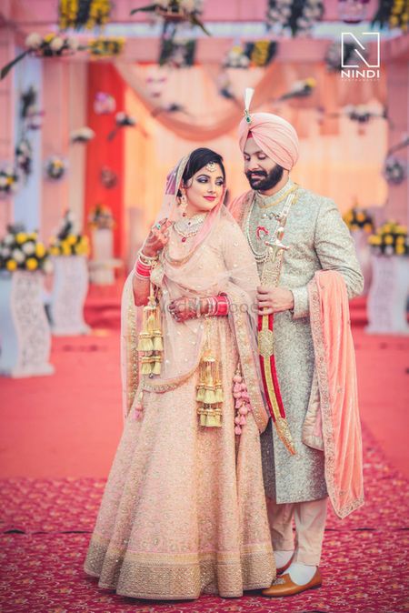 Photo of Coordinated Sikh bride and groom in peach
