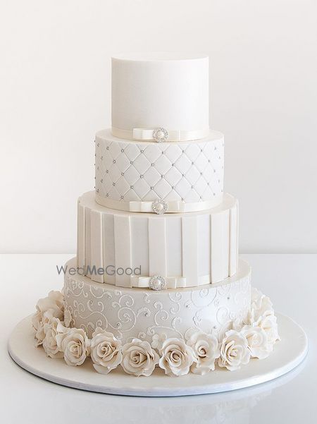 Photo of 4 tiered white wedding cake with roses