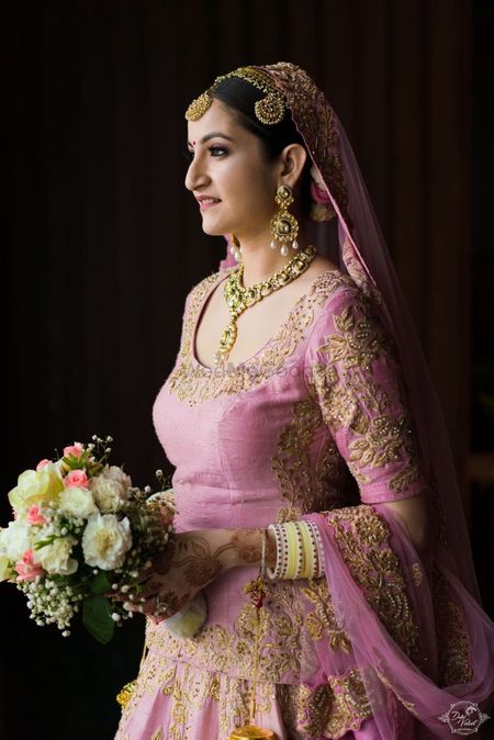 Bride in onion pink lehenga with bouquet