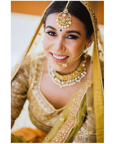 Photo of A bride in golden lehenga and minimal jewelry