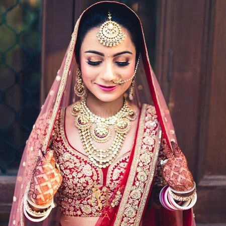 Bride in red acting shy holding dupatta
