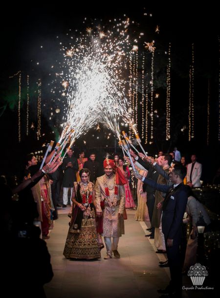Photo of Couple entering in red with guests holding cold pyros