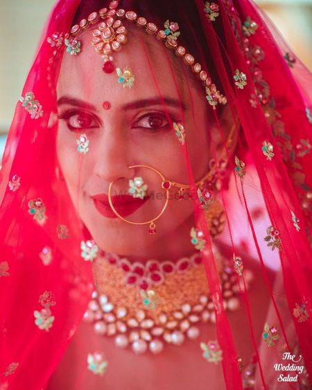 Photo of bride with her dupatta as a veil shot looking into camera