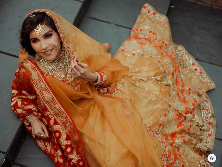 A bride in a yellow outfit with a contrasting dupatta 