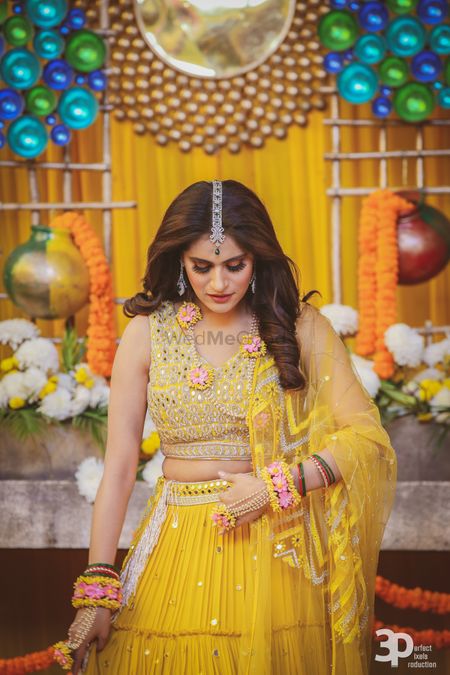 Yellow mehendi lehenga with open hair and floral jewellery