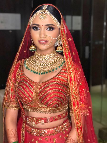 Bride wearing dewy base and nude lips with her red lehenga