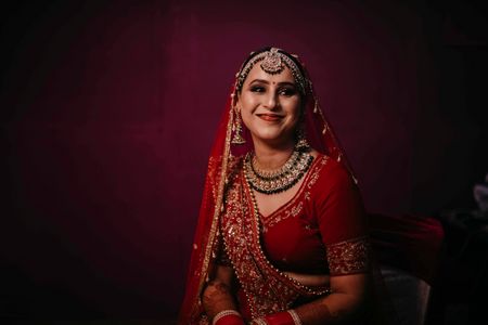 Photo of Smiling bridal portrait in traditional red lehenga!