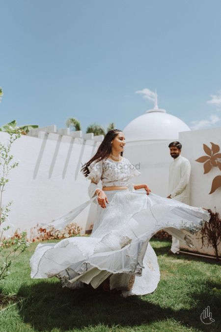 Photo of A bride twirls in a white wedding outfit during her pre wedding
