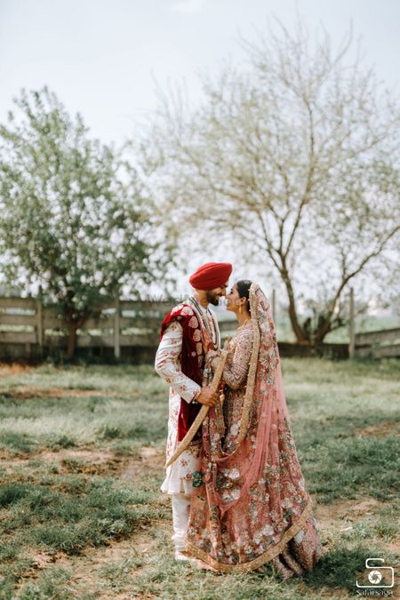A Sikh couple posing in the fields on their wedding day.