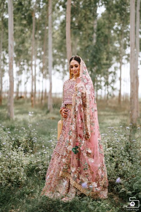 Bride wearing a fully embellished pink bridal lehenga.