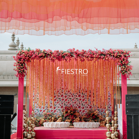 Haldi decor for seating in pink and orange hues with hanging florals 