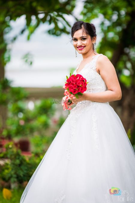 Photo of Christian Bride with White Lace Lehenga and Red Bouquet