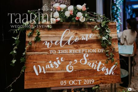 A rustic wooden signage detailed with flowers for entrance
