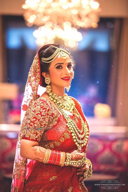 Bride in red bridal saree wearing layered jewellery  