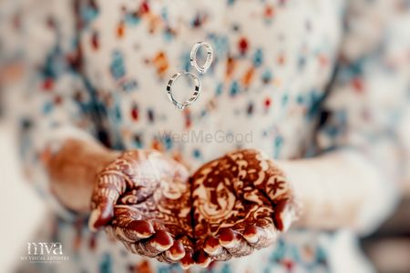Bride tossing engagement rings with mehendi laden hands 