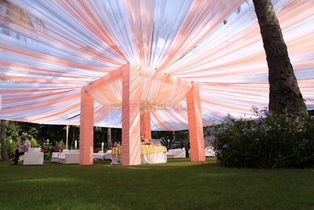 Photo of Pastel peach mandap with fabric tent