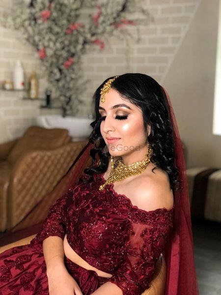 A beautiful bridal makeup in maroon off-shoulder lehenga. 
