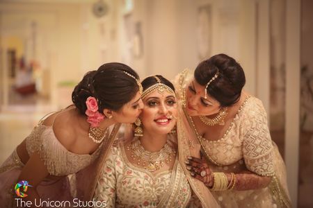 Bride with sisters kissing her
