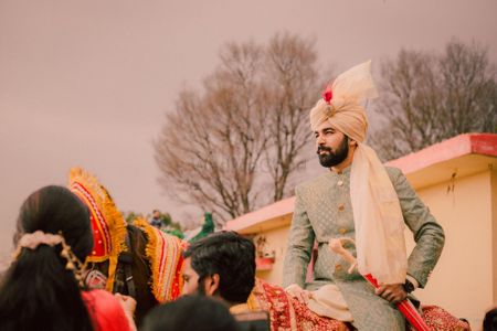Groom in unique safa and grey sherwani entering on horse 