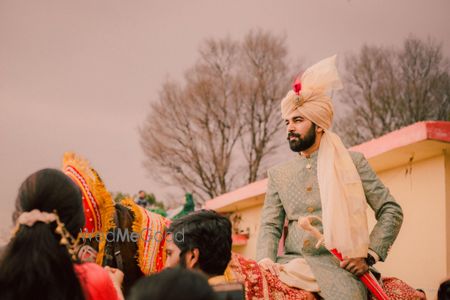 Groom in unique safa and grey sherwani entering on horse 