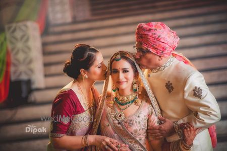 bridal portrait with her parents kissing her 