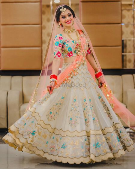 A bride in white and coral lehenga twirling