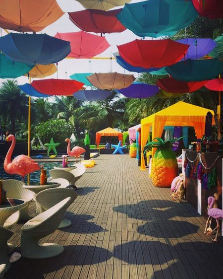 Tropical theme mehendi decor with hanging parasols