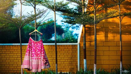 Bridal lehenga photography with bright pink one on hanger 
