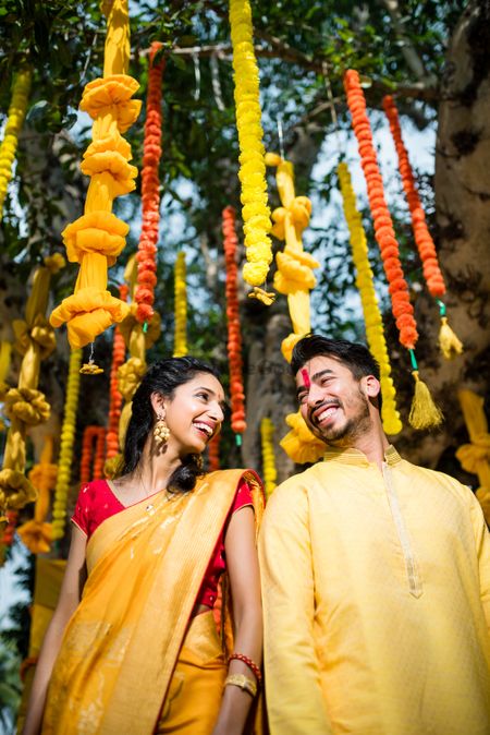 Genda phool decor for haldi with couple in yellow 