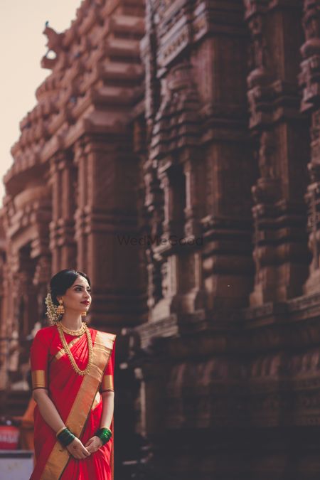 A south indian bride in a red saree poses for her bridal portrait.