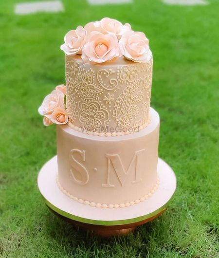 Photo of A pastel pink cake decorated with florals and the couple's initials.