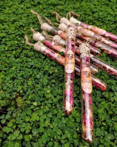 Glass tubes filled with dried rose petals as wedding favours for guests.