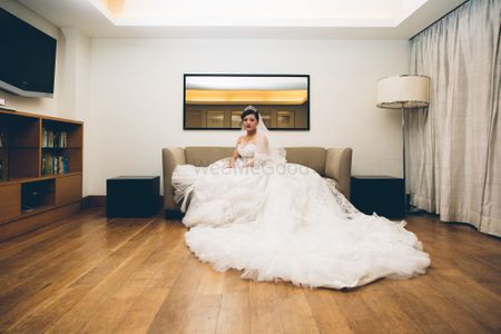 Photo of Christian bride sitting on couch with gown flared out