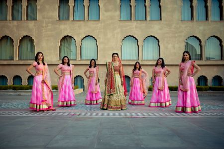 Photo of Fun bride and bridesmaid shot with bridesmaids in coordinated lehengas