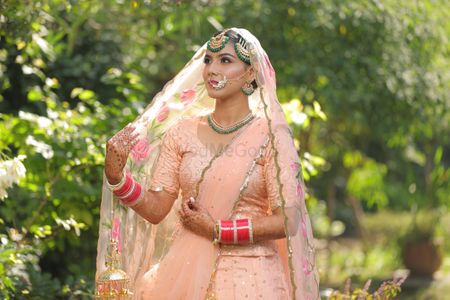 Photo of Sikh bride with peach lehenga and green jewellery