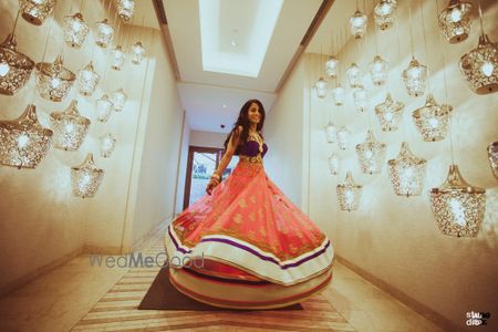 Photo of Bride twirling in orange layered lehenga