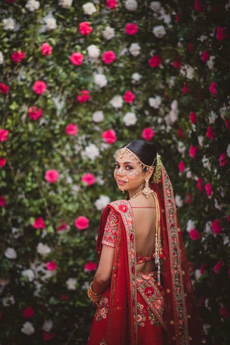Photo of Bride looking back against floral wall