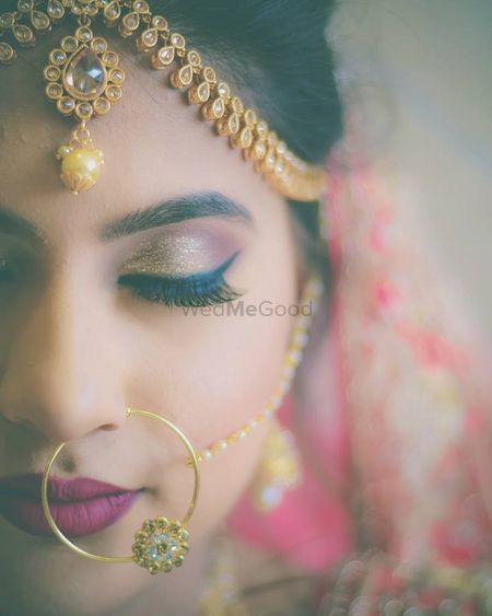 Plum and gold bridal makeup look with deep lips