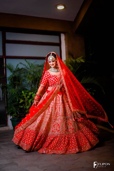 Photo of A stunning bride twirling in her beautiful red lehenga.