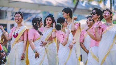 Coordinated bridesmaids in white and gold sarees with pink blouses