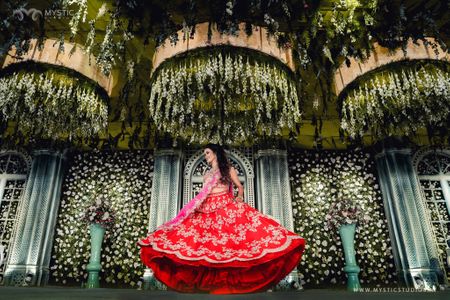 Photo of bride twirling on stage in her red and pink lehenga