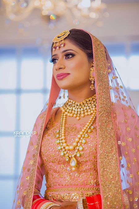 Sikh bride wearing light pink and gold bridal jewellery