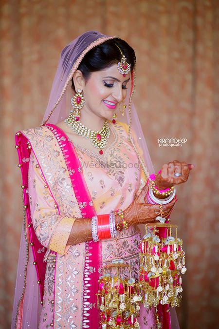 Sikh bride in peach wearing kaleere with pompoms