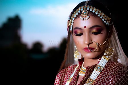 A bride in maroon lehenga and pearl jewelry