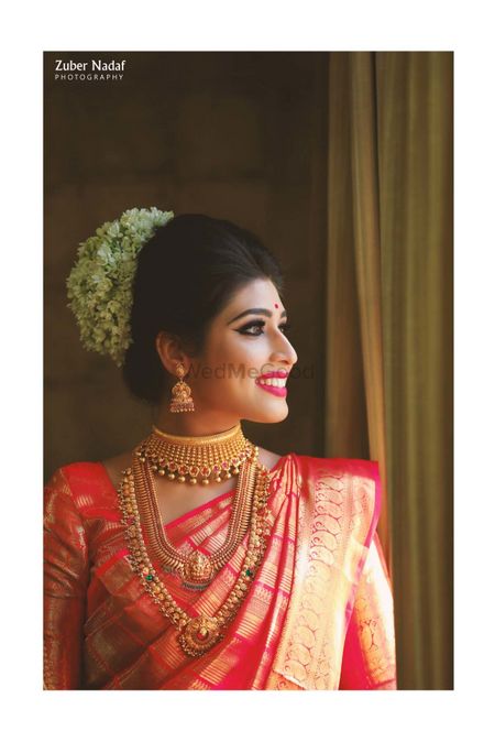 Photo of A south Indian bride in red kanjeevaram with temple jewelry and gajra in her hair
