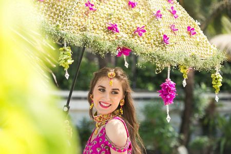 Photo of Bride entering under a floral umbrella on mehendi